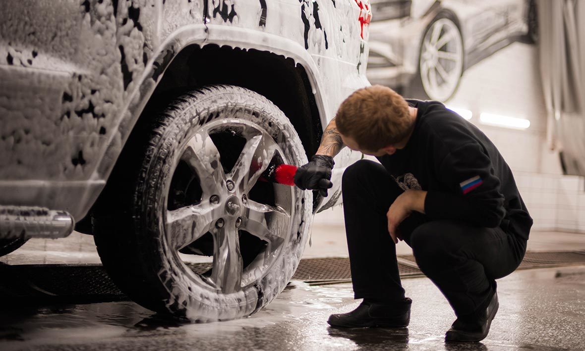 На фото специалист детейлинга вычищает грязь из труднодоступных мест на колесном диске автомобиля.
