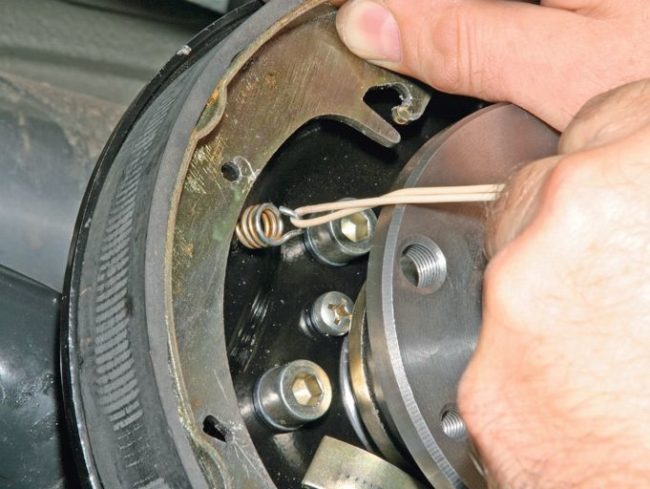Натягивание прижимной пружины на новую тормозную колодку в механизме заднего колеса на Лада Калине